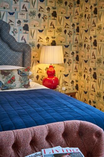 a bedroom with a bed with a blue comforter and a lamp at Hotel du Vin Cheltenham in Cheltenham