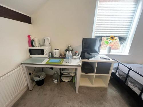 a desk with a computer on it in front of a window at Large 3 Bed House, 2 Bathrooms in Ilkeston