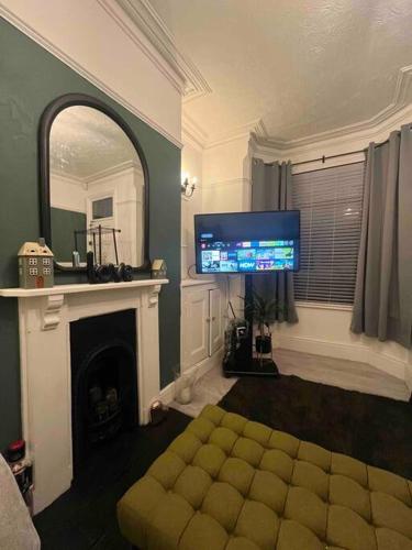 a living room with a tv and a couch and a mirror at Sleeps up to 8 Free Parking Large Town House 3 Bed, 2 Bathrooms Private Locked Garden In-between Nottingham & Derby Contractor Friendly in Ilkeston