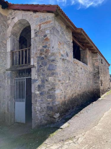 - un vieux bâtiment en pierre avec une porte et un balcon dans l'établissement Παραδοσιακή Κατοικία στο Μαίναλο, à Alonistaina