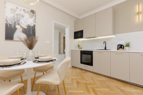 una cucina con armadi bianchi e tavolo e sedie bianchi di Bright & Elegant Apartment Warsaw by Renters a Varsavia