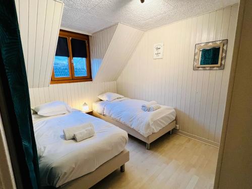 two beds in a small room with two windows at Gîte Aux Quatre Vents avec Terrasse in Rouffach