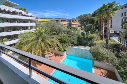 Cet appartement dispose d'un balcon avec une piscine et des palmiers. dans l'établissement Appartement , piscine, terrasse, proche croisette, à Cannes