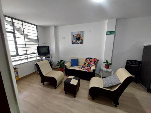 a living room with chairs and a couch and a tv at Apto vacacional DENIS T in Tunja