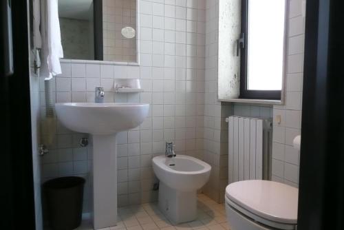 a white bathroom with a sink and a toilet at Club Hotel in Mestre