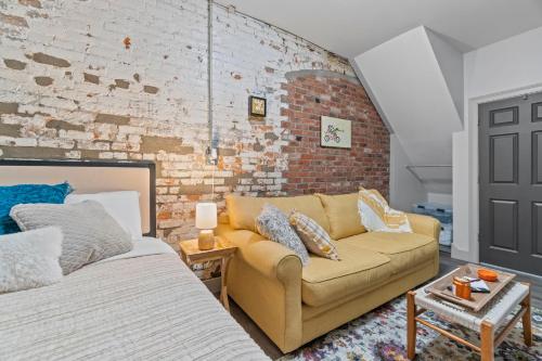 a living room with a couch and a brick wall at The 418. An 1866 Build with Modern Comforts in Fort Wayne