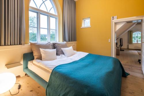 a bedroom with a large bed with a blue blanket at Nørre Vosborg Hotel & Gastronomi in Vemb