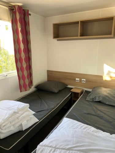 two beds in a small room with a window at Mobilhome La Carabasse Vias Plage in Vias