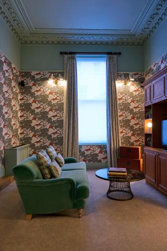 a living room with a green couch and a window at Hotel du Vin Cheltenham in Cheltenham