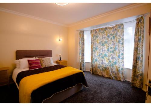 a bedroom with a bed with a yellow blanket and a window at 4 Bedroom Home in Tranquil Gravesend Location in Gravesend
