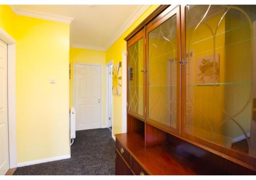 a bathroom with yellow walls and a wooden cabinet at 4 Bedroom Home in Tranquil Gravesend Location in Gravesend