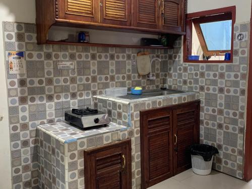 - une cuisine avec une cuisinière et du carrelage au mur dans l'établissement Bukittinggi Homestay, à Bukittinggi