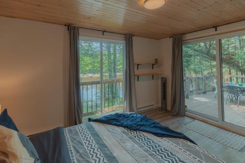 The Phoenix - riverside chalet with beach في مونت تريمبلانت: غرفة نوم بها سرير ونافذة كبيرة