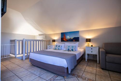 a bedroom with a large bed and a couch at Hôtel Les Créoles in Saint-Gilles les Bains