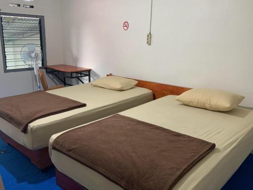 Zimmer mit 2 Betten und einem Tisch mit einem Ventilator in der Unterkunft Bukittinggi Homestay in Bukittinggi