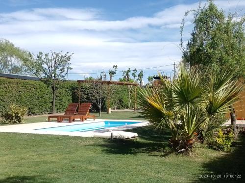 uma piscina num quintal com dois bancos ao lado em La Cabaña de Eco Verde em San Rafael