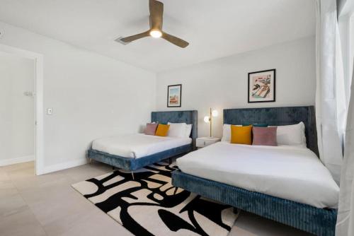 a bedroom with two beds and a ceiling fan at Rather Be Designer Casa by Rather Be Properties in Desert Hot Springs
