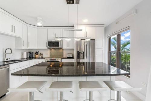 a kitchen with white cabinets and a large island with stools at George Town Villas #117 in George Town