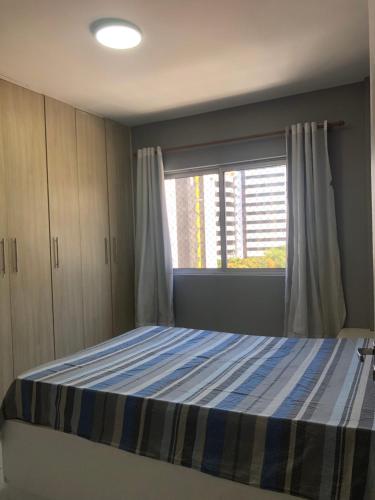 1 dormitorio con cama y ventana en Apt a 150m da melhor faixa de praia da Ponta Verde com 2 quartos 2 banheiros cozinha sala de estar garagem coberta 2 elevadores portaria 24h RECENTEMENTE REFORMADO Acomoda até 5 Pessoas, en Maceió