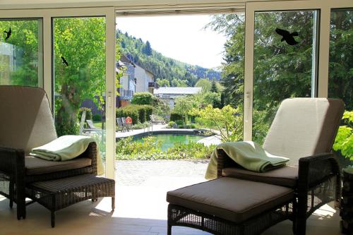 a screened in porch with chairs and a view of a pool at Flair Hotel Nieder in Bestwig