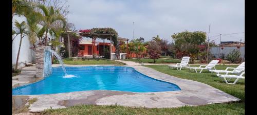 una piscina con una fuente de agua en un patio en Hospedaje Campestre Los Suspiros, en Sunampe