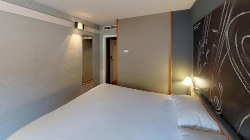 a bedroom with a large white bed in a room at ibis Dinant Centre in Dinant