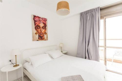 ein Schlafzimmer mit einem weißen Bett und einem Gemälde an der Wand in der Unterkunft 2Bedroom Suite with Balcony YonaHotel in Tel Aviv
