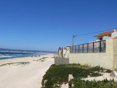 a building on the beach with the ocean in the background at Dream House On The Beach in Figueira da Foz