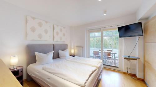 a bedroom with a white bed with a flat screen tv at FeWo in direkter Strandlage mit eingeschränktem Meerblick, Villa Freia 09, Binz in Binz