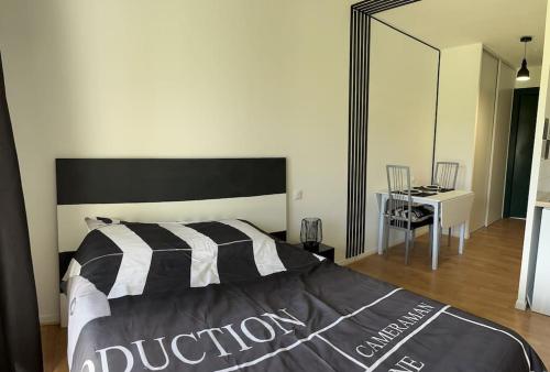 Schlafzimmer mit einem schwarzen und weißen Bett und einem Tisch in der Unterkunft Studio avec piscine près d'Honfleur in Équemauville