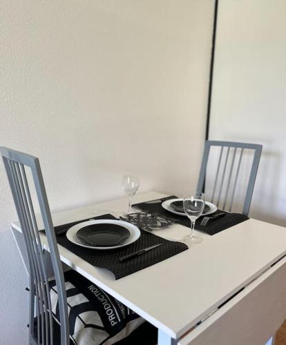 - une table avec deux chaises, une assiette et des verres à vin dans l'établissement Studio avec piscine près d'Honfleur, à Équemauville