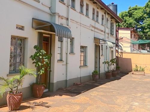 een wit gebouw met potplanten op een straat bij Hotel Acacia City in Kampala