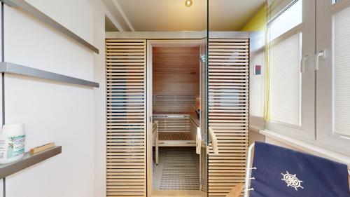 a walk in shower in a room with wooden doors at FeWo in direkter Strandlage mit eingeschränktem Meerblick, Villa Freia 09, Binz in Binz