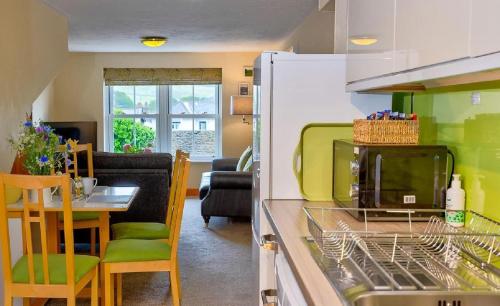 a kitchen with a dishwasher and a living room at Howgills Apartments in Sedbergh
