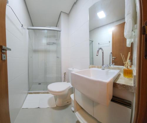 Baño blanco con lavabo y aseo en Barra Stella do Mar Studio, en Salvador