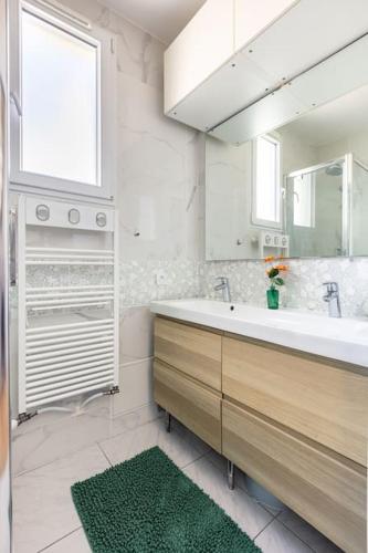 une salle de bain avec un lavabo et un grand miroir dans l'établissement Maison 3 chambres aux portes de Paris, à Arcueil