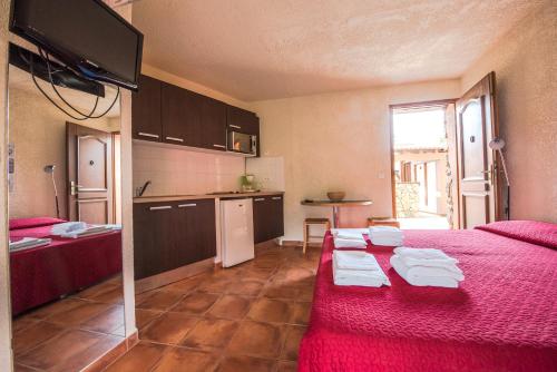 a room with a red bed and a kitchen at U Casinu in Piana