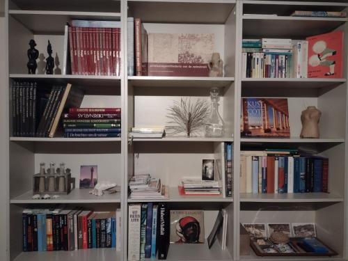 a white book shelf filled with lots of books at Prince's165 in Knokke-Heist