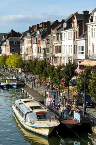 a boat docked at a dock in a river with buildings at ibis Dinant Centre in Dinant