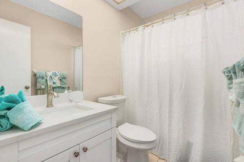 a white bathroom with a toilet and a sink at Naples Paradise Near The Beach! in Naples