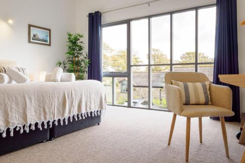 Un dormitorio con una cama y una silla y una ventana. en Sennen, en Budock Water