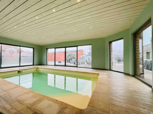 - une piscine vide dans une pièce dotée de murs verts et de fenêtres dans l'établissement Villa d’architecte avec piscine chauffée, à Ligny-en-Cambrésis