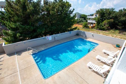 a swimming pool on a patio with lounge chairs at Oceanside, Private Pool, Hot Tub, Community Pool, CD7, Sandfiddler Lodge in Duck