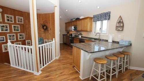 a kitchen with a island with stools in it at Oceanside, Private Pool, Hot Tub, Community Pool, CD7, Sandfiddler Lodge in Duck