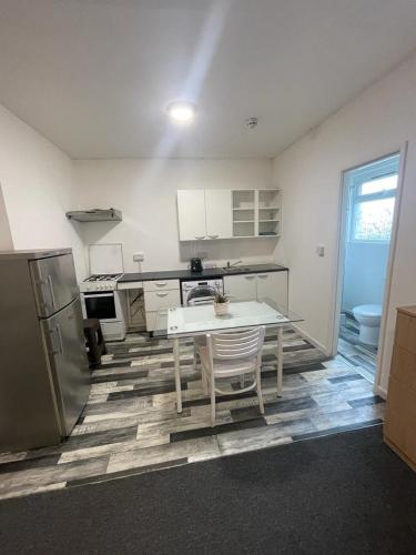 a white kitchen with a table and a refrigerator at Nice Studio Flat in North Acton in London