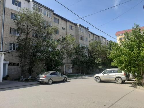 twee auto's geparkeerd op een parkeerplaats voor een gebouw bij 2-комнатная квартира в центре города in Atıraw