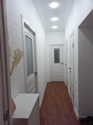een hal met witte muren en houten vloeren en witte deuren bij 2-комнатная квартира в центре города in Atıraw