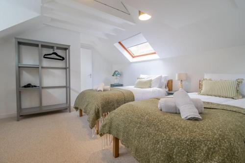 a bedroom with three beds and a skylight at Henry Bell - Cosy 2-bedroom cottage in Helensburgh