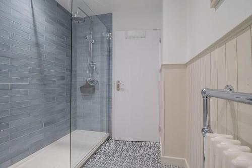 a shower with a glass door in a bathroom at Henry Bell - Cosy 2-bedroom cottage in Helensburgh