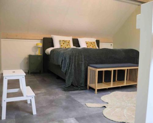 um quarto com uma cama grande e um banco em GeinLust B&B De Zonnebloem em Abcoude